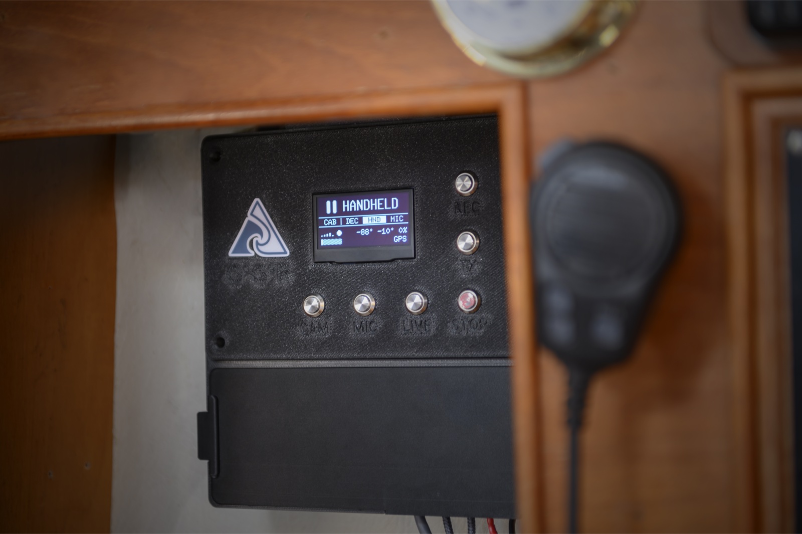 The TriPeak on-board unit mounted in a boat's cabin, its display showing the handheld camera selected, with CAM, MIC, LIVE, REC, TX and STOP buttons